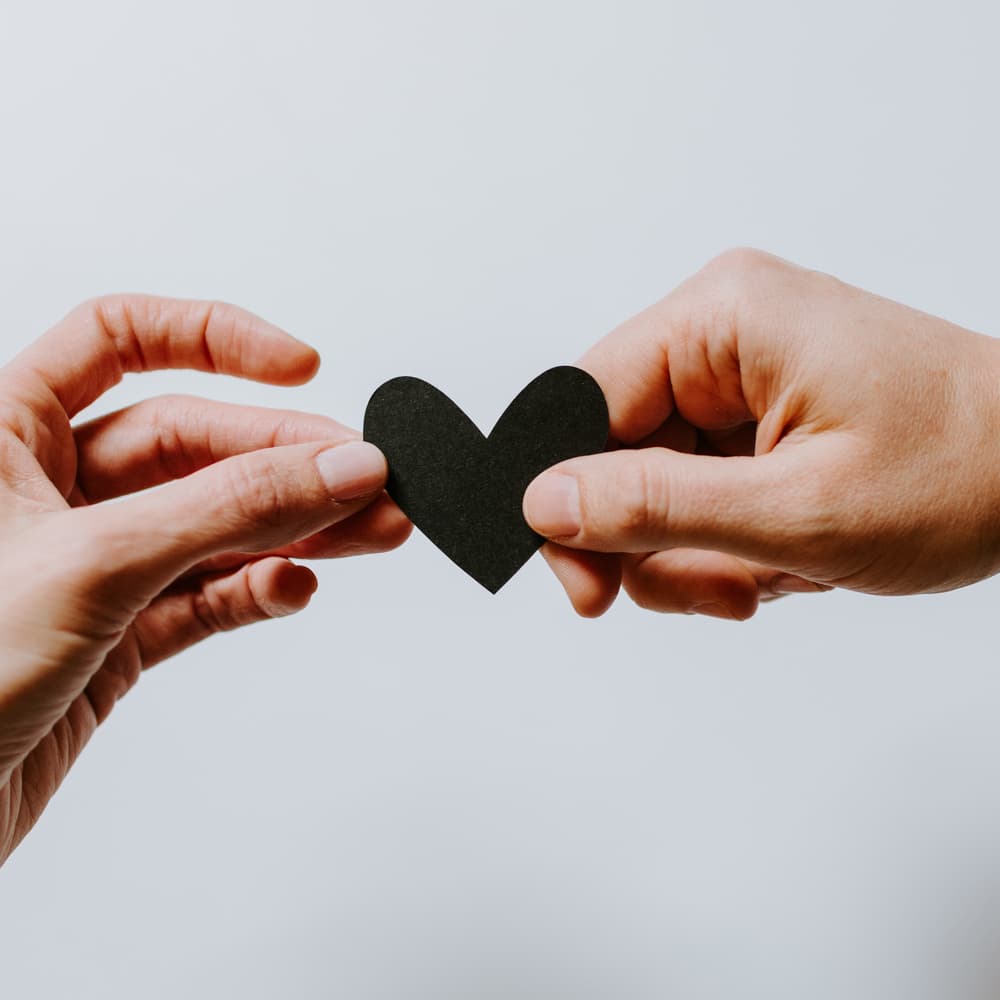 Manos compartiendo un corazón de papel